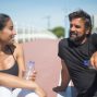 Two friends taking a break during outdoor exercise on a sunny day, hydrating and chatting.