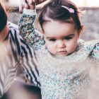 woman holding girl while learning to walk taken at daytime