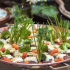 An artistic presentation of vegetables including broccoli, carrots, and greens on a copper platter.